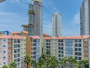 Ein mehrgeschossiges Wohngebäude mit Balkonen, im Hintergrund ein moderner Hochhaus und ein klarer Himmel.
