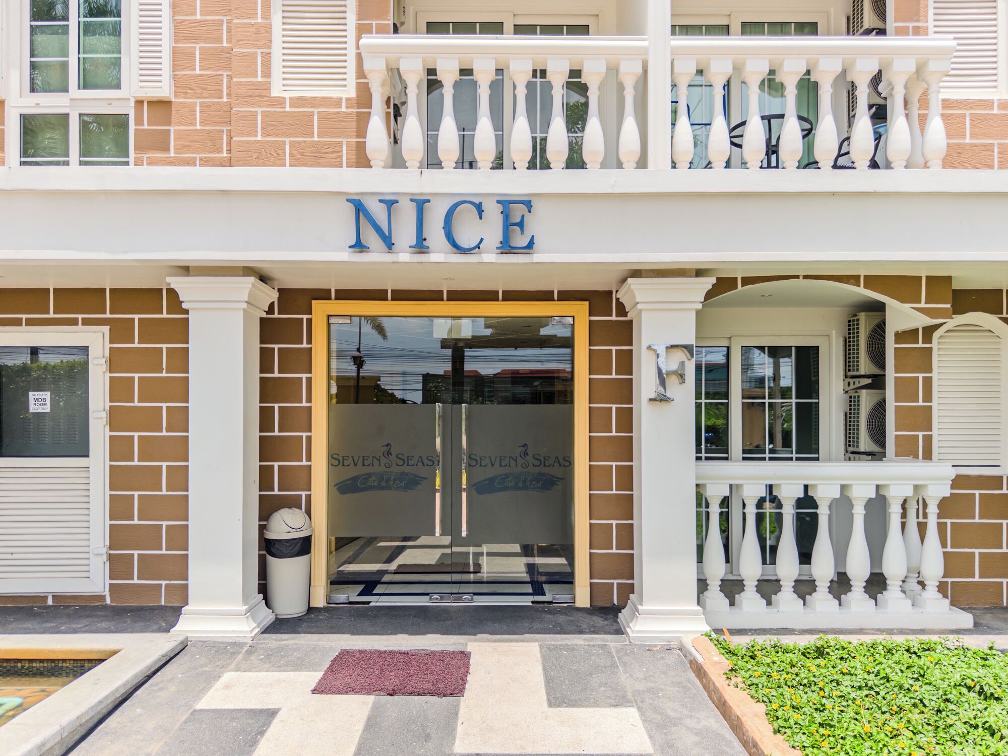 A hotel entrance with a sign reading 'NICE,' a glass door, and a brick facade.