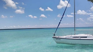 Un barco llamado 'MOTOKO' anclado en aguas turquesas cristalinas, con una estructura de techo de paja sobre él.