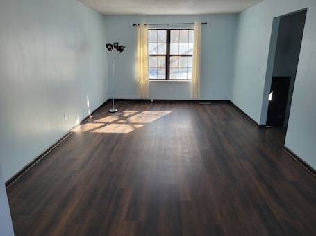 A room with wooden flooring, a standing lamp, a window with curtains, and a door.. Marvelous 3-room townhome in Raytown. 5-8 min from stadiums, World Cup!