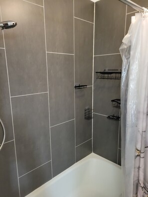 A bathroom with a shower, a bathtub, and tiled walls. - Marvelous 3-room townhome in Raytown. 5-8 min from stadiums, World Cup! (Raytown)