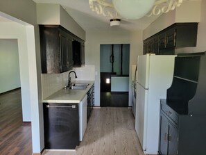 A kitchen with dark cabinets, a white refrigerator, and a wooden floor. - Marvelous 3-room townhome in Raytown. 5-8 min from stadiums, World Cup! (Raytown)