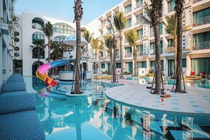 A hotel pool area with a slide, palm trees, and a modern building with balconies. - Sugar Marina Hotel Pop, Kata Beach (Karon)