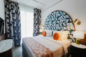 A hotel room with a bed, two bedside tables, a TV, and a geometric-patterned headboard.