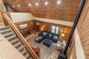 Un interior de madera con un sofá, una chimenea y una escalera.