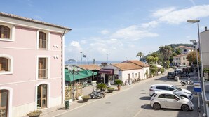 Vista de la calle con edificios, coches aparcados y cielo despejado.