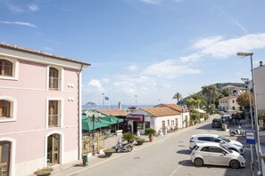 A street view with buildings, parked cars, and a clear sky. - Casa di Nonna Albina (Cavo)