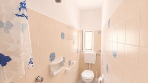Un baño con inodoro, bidé, ducha y ventana.