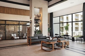 A modern lobby with a sofa, chairs, a coffee table, and a decorative sculpture. - Hotel Riu Palace Swahili - Adults Only - All Inclusive (Nungwi)