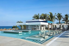 A modern pool area with clear water, lounge chairs, and umbrellas, overlooking the ocean. - Hotel Riu Palace Swahili - Adults Only - All Inclusive (Nungwi)