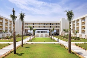 A modern hotel with a central courtyard, surrounded by palm trees and a symmetrical building facade. - Hotel Riu Palace Swahili - Adults Only - All Inclusive (Nungwi)