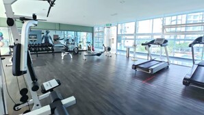 Un gimnasio con máquinas de cardio, equipo de pesas y un amplio ventanal.