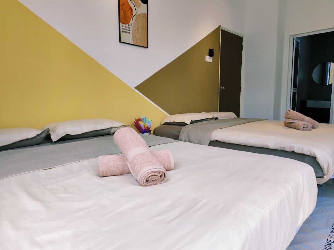 A hotel room with two beds, each with a neatly folded towel, a pillow, and a blanket.