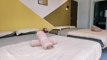 A hotel room with two beds, each with a neatly folded towel, a pillow, and a blanket.