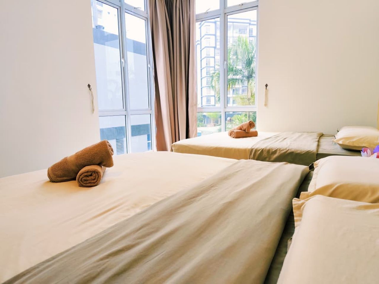 Een hotelkamer met twee bedden, een raam met gordijnen en uitzicht op gebouwen.