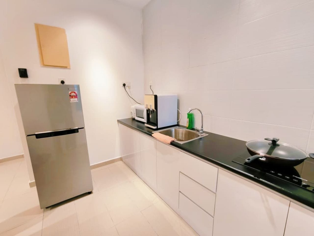 Eine kleine Küche mit Kühlschrank aus Edelstahl, einer Mikrowelle, einem Spülbecken und einem Herd.