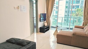 Una sala moderna con un sofá, una mesita, un televisor y un balcón con vistas a edificios.