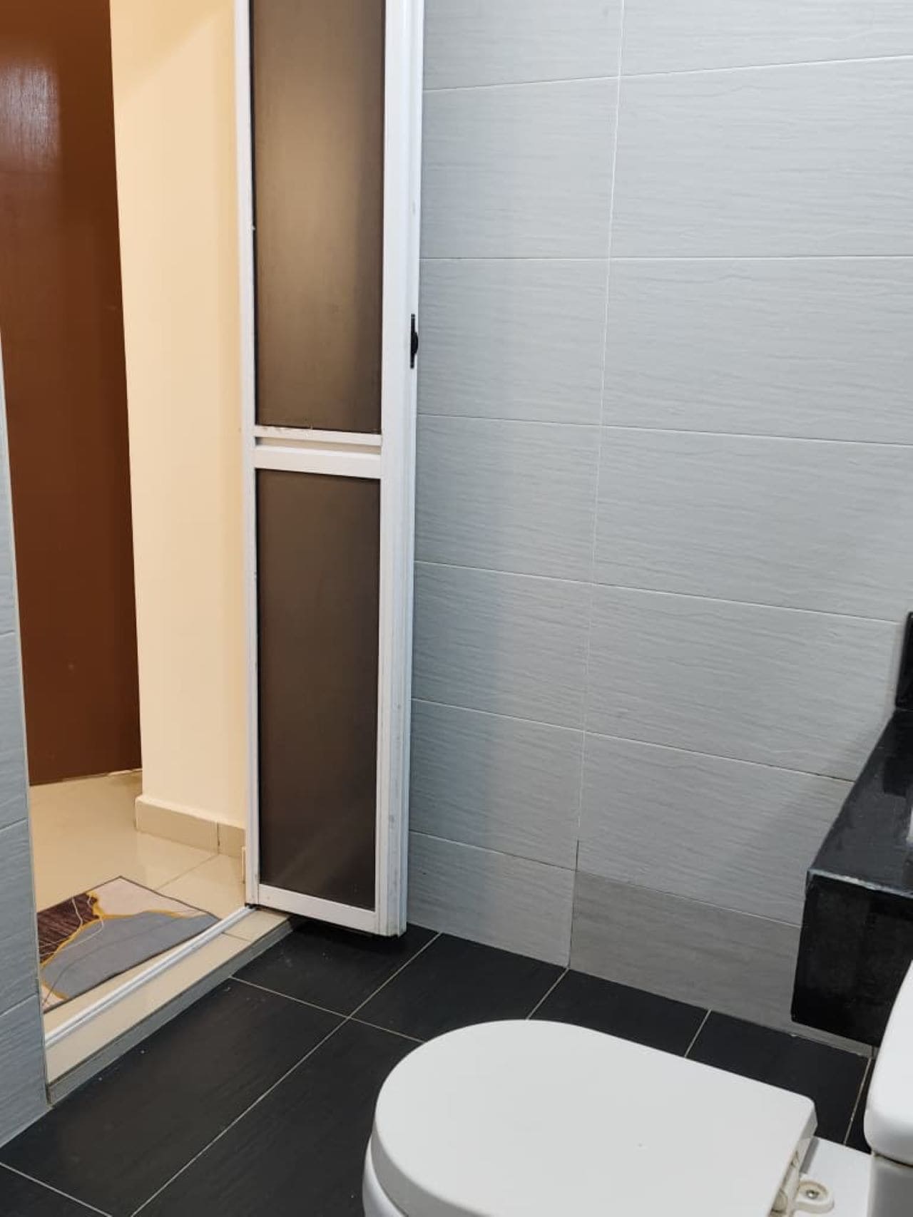 A bathroom with a toilet, a shower area, and a tiled floor.
