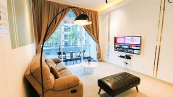 A modern living room with a sofa, ottoman, and a flat-screen TV mounted on the wall.