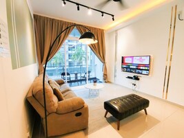 Una sala moderna con sofá, reposapiés y un televisor de pantalla plana montado en la pared.