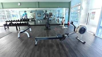 A gym with exercise equipment, a mirror, and a clock on the wall.