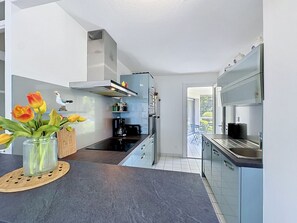 A modern kitchen with a central island, built-in appliances, and a view to the outside. - Le Vallon by Interhome (Pornic)