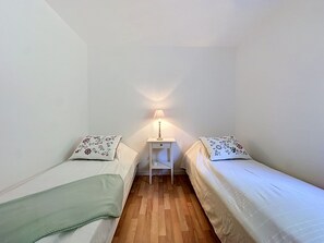 Eine kleine, einfache Unterkunft mit zwei Betten, einem Nachttisch und einer Lampe.