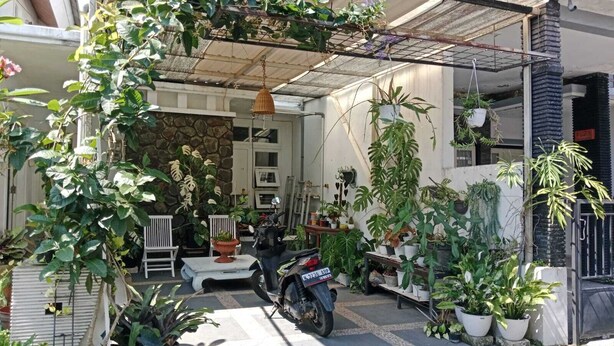 Un espacio al aire libre techado con plantas en macetas, una motocicleta y un muro de piedra.