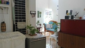 Una habitación con cama, escritorio, silla, armario y ventana con persianas.