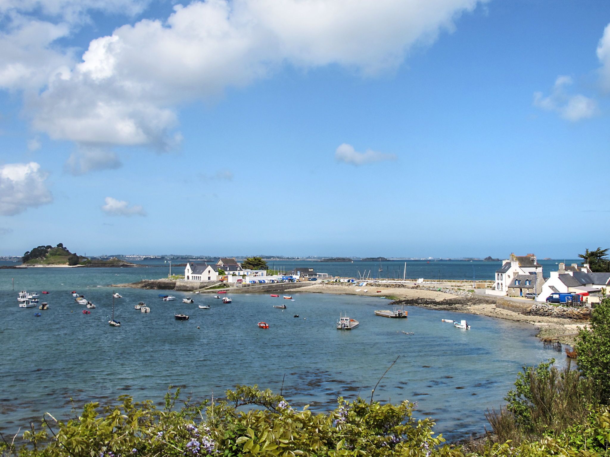 A coastal town with boats in the water, buildings along the shore, and a clear sky.