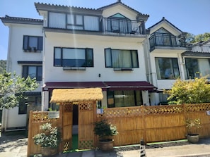 A traditional Japanese-style building with a thatched entrance, wooden lattice fence, and potted plants. - Hangzhou qiushan dashu minsu (Hangzhou)