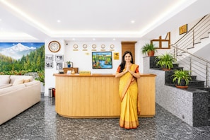 A reception desk with a clock, framed photos, and a painting on the wall. - Hotel Royal Inn Gangtok (Gangtok)