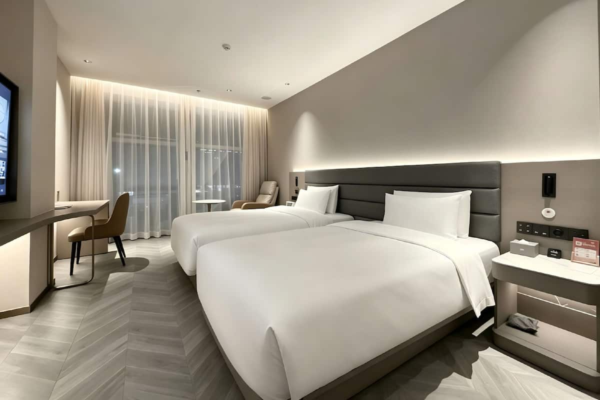 Ein modernes Hotelzimmer mit einem großen Bett, einem Schreibtisch, einem Sessel und einem Fernseher.