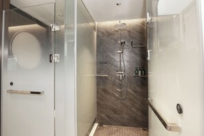 Uma casa de banho moderna com cabine de duche em vidro, parede de mármore e um porta-toalhas visível.