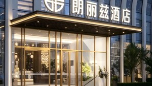 Una entrada de hotel moderna con fachada de vidrio, un logotipo destacado y un área de acceso bien iluminada.