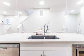A modern kitchen with a stainless steel dishwasher, a double sink, and a built-in oven. - Luxury Spacious 3BR Retreat | King Bed | Fast WiFi | Free Parking | Near Shops (Calgary)