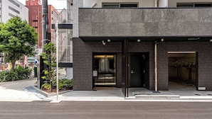 A modern building with a dark brick facade, a glass entrance, and a visible interior with metal railings. - Eslead Hotel Namba East Annex (Oosaka)