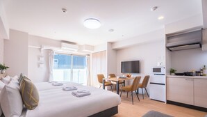A hotel room with a bed, a dining table with chairs, a kitchen area with a microwave, and a TV mounted on the wall. - Eslead Hotel Namba East Annex (Oosaka)