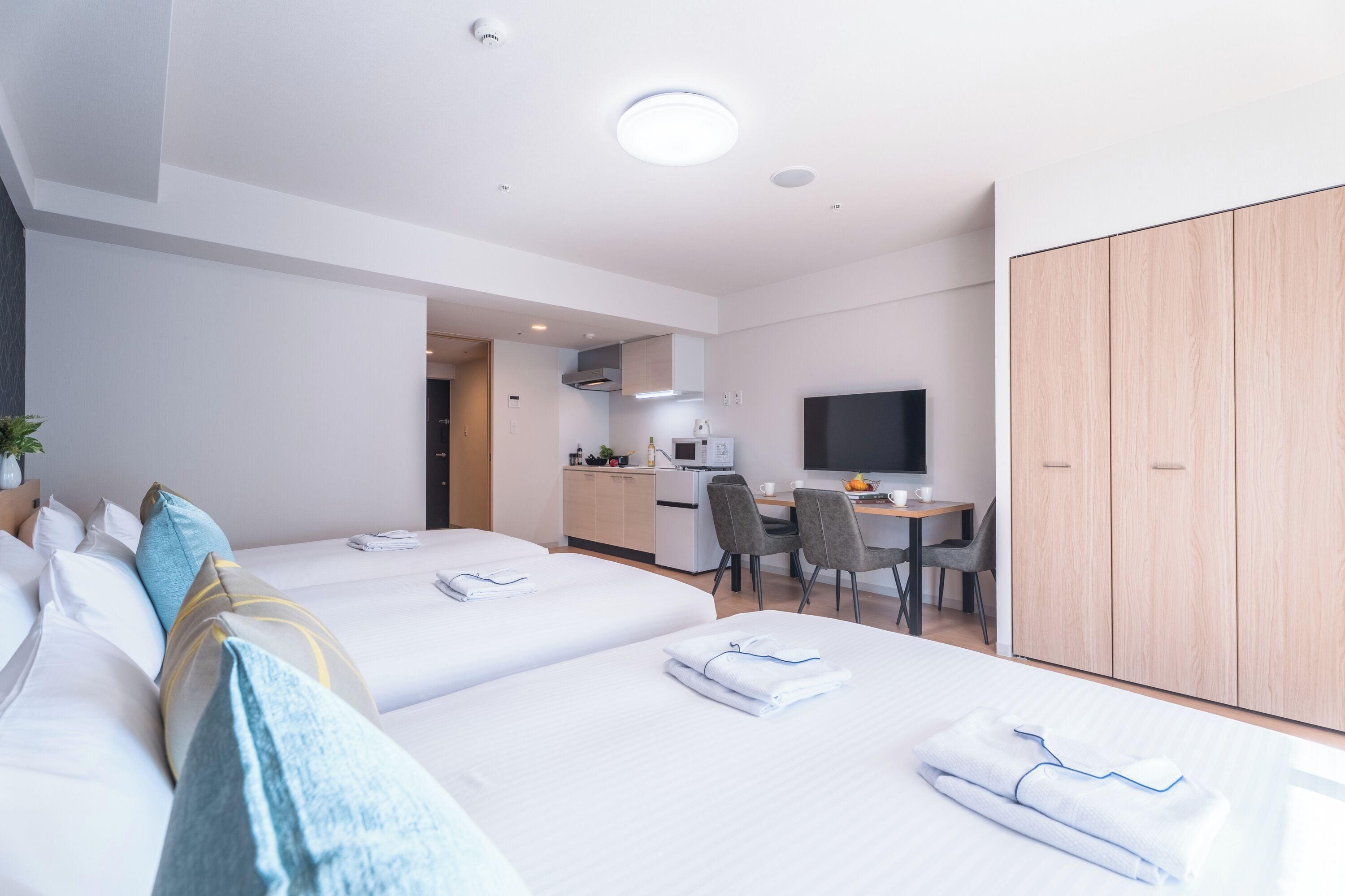 A hotel room with two beds, a desk, a TV, and a wardrobe.