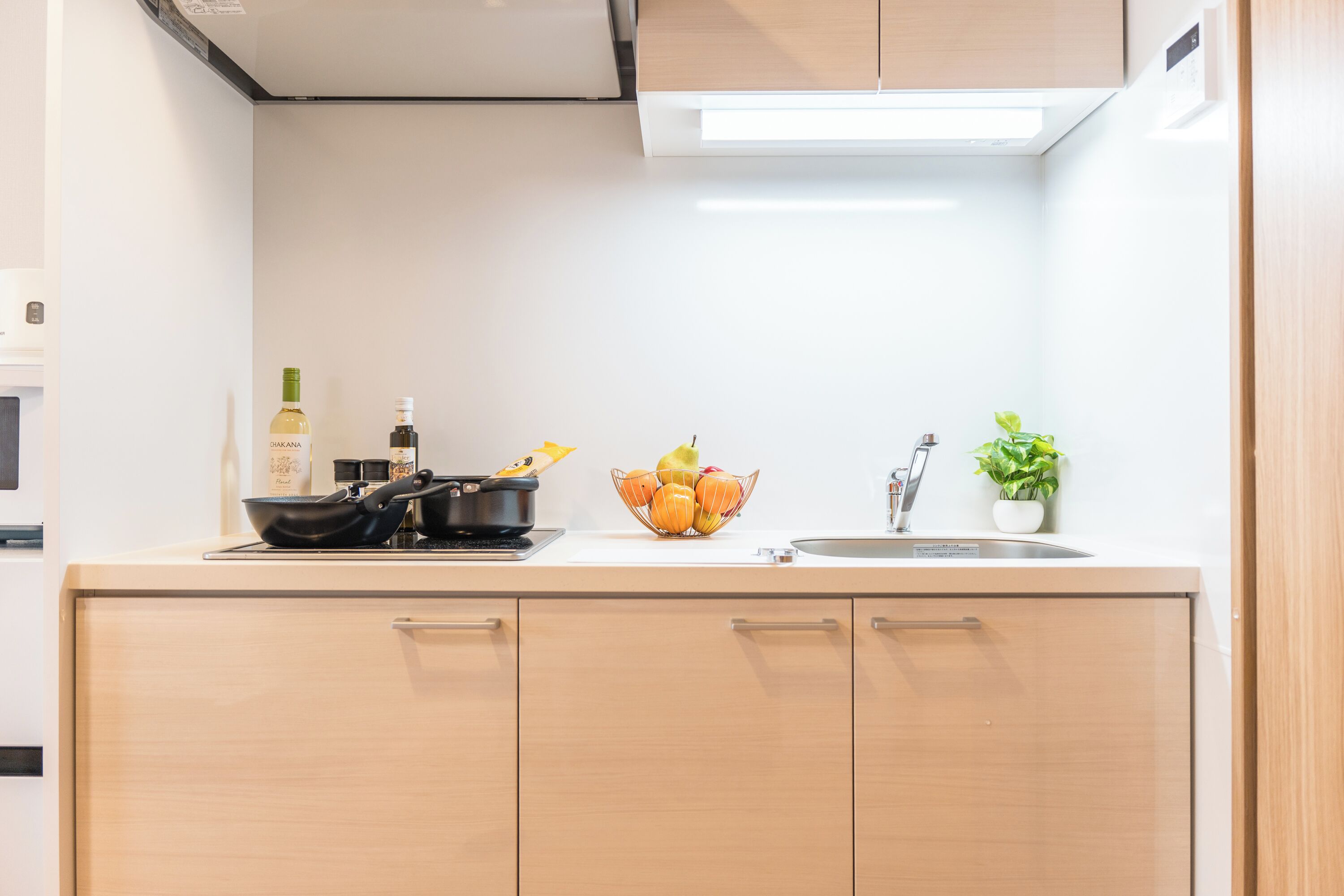 A modern kitchen with a stove, a sink, and a bowl of fruit.