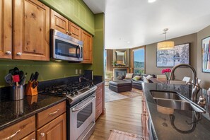 A kitchen with wooden cabinets, a stainless steel microwave, and a gas stove. - Purgatory Alpine Retreat | Walk to Lifts & Base Area | Pool/Hot Tub (Durango)