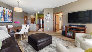 Een moderne woonkamer met een eetgedeelte, keuken en een aan de muur bevestigde televisie.