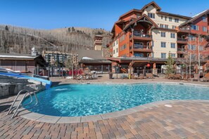 A hotel with a swimming pool, outdoor seating, and a mountainous backdrop. - Purgatory Alpine Retreat | Walk to Lifts & Base Area | Pool/Hot Tub (Durango)