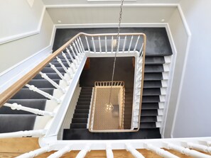 A staircase with a hanging swing chair, white balusters, and a wooden handrail.