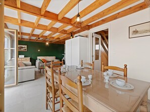 Ein Essbereich mit einem Holztisch, gedeckt für vier Personen, einer Couch und einer Treppe, die zu einer weiteren Ebene führt.