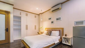 Un dormitorio con cama, armario, mesita de noche, lámpara y aire acondicionado instalado.
