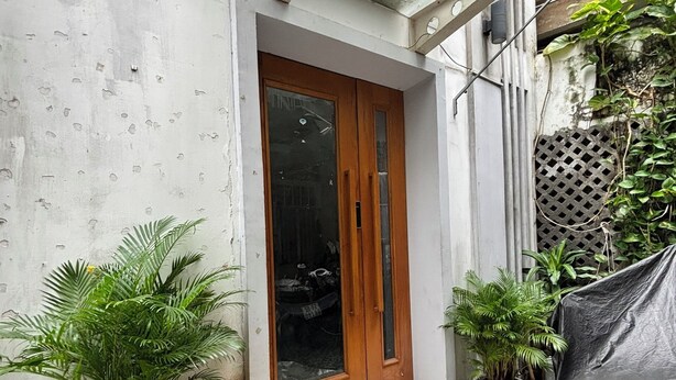 Entrada de un edificio con puerta de madera, escalones de piedra y plantas en macetas.
