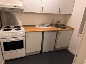 Cozinha com fogão, forno, pia e armários.