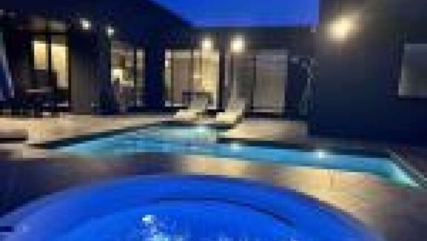 A modern indoor swimming pool with a hot tub, lounge chairs, and a glass-enclosed area. - Queen + 2 Double Beds + 2 Futons (ichinomiyamachiitinomiya)