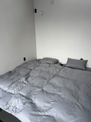 A single bed with a grey duvet, a white wall, and a small light switch on the wall. - Private villa in Ichinomiya-cho, Chiba, sauna, pool, Jacuzzi (ichinomiyamachiitinomiya)